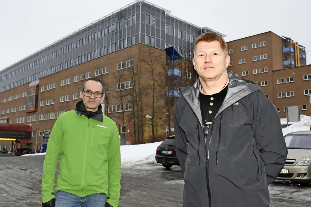 Et par menn som står i snøen foran en bygning