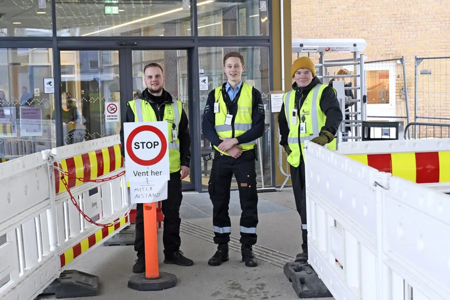 En gruppe mennesker iført sikkerhetsvester og står ved siden av et skilt
