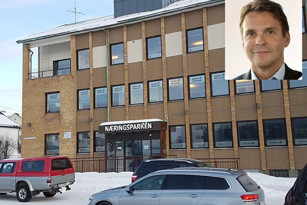 En person som står foran en bygning med biler parkert foran