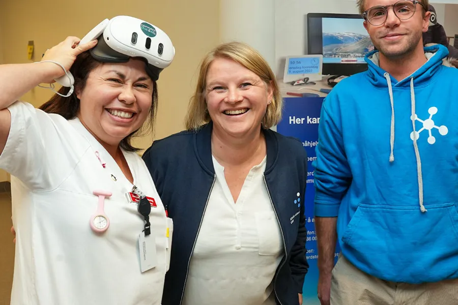 Tre personer, den til venstre med VR-briller på