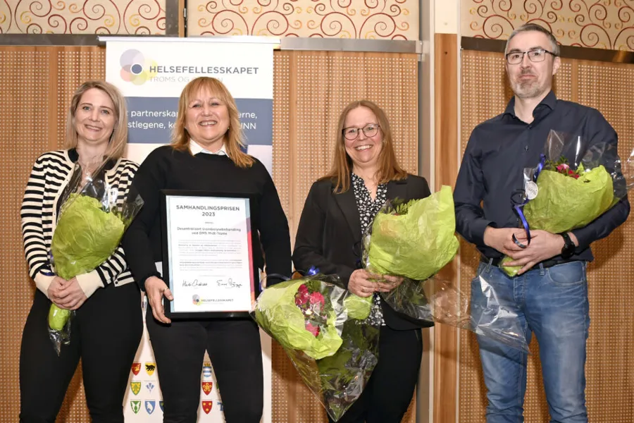 Tre personer som holder blomster og en person holder en diplom