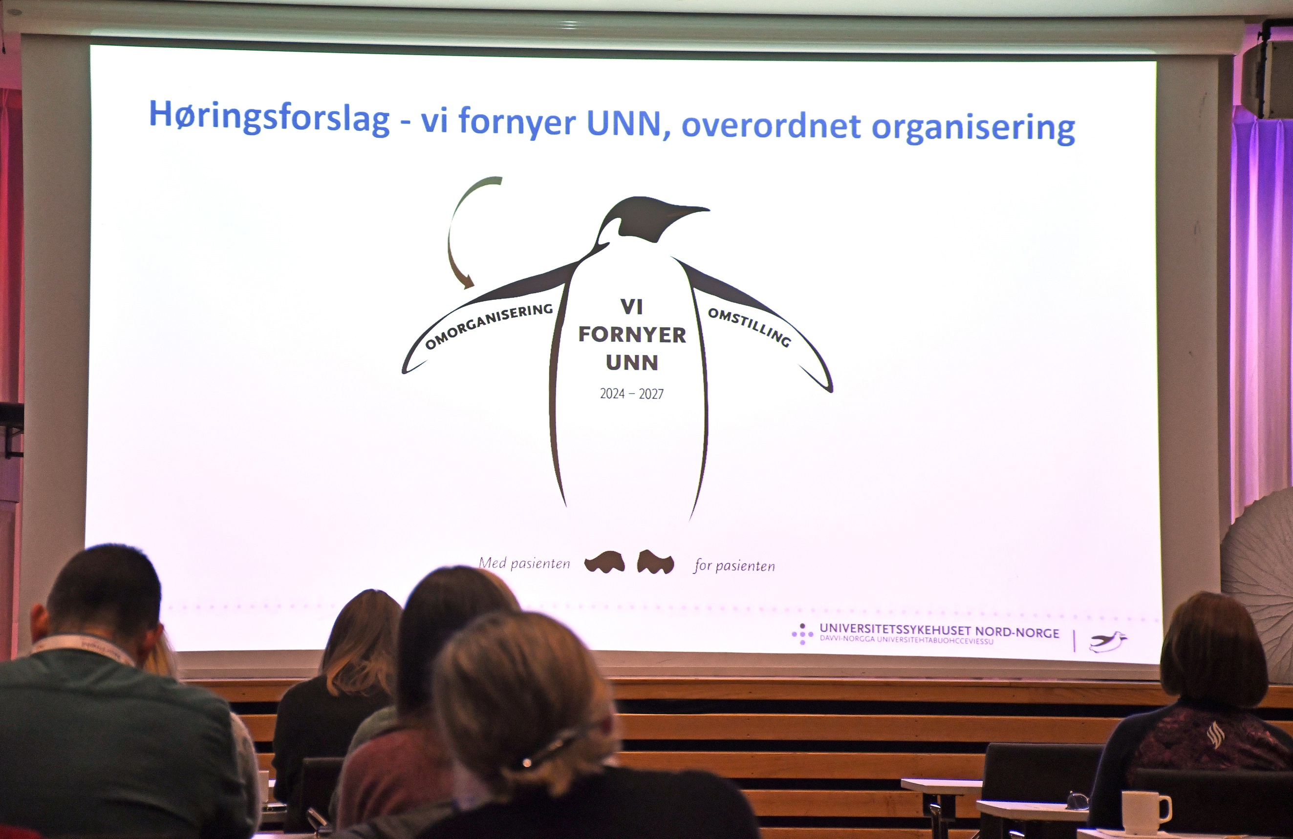 En gruppe mennesker som sitter foran en projeksjonsskjerm