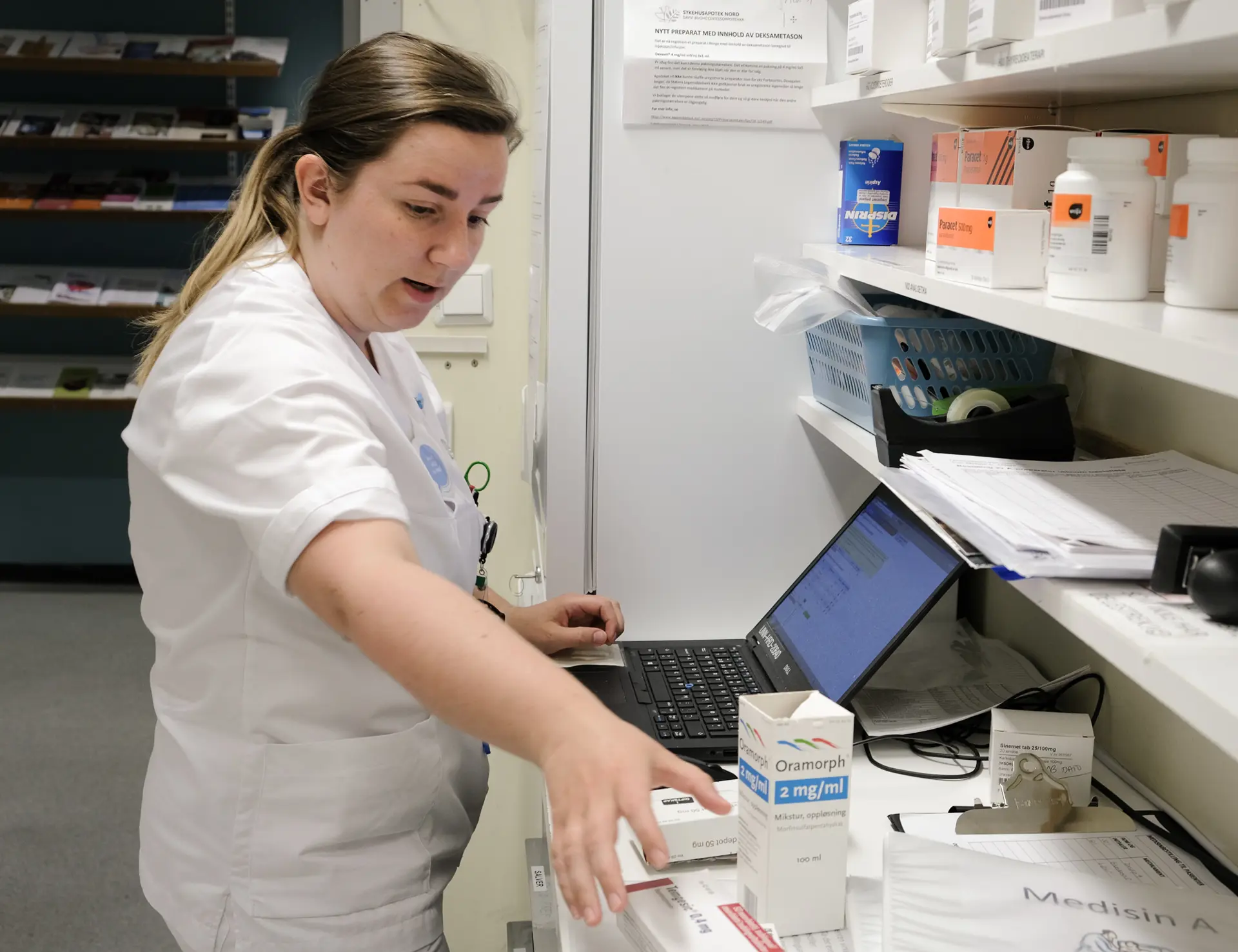 En person som jobber på en bærbar datamaskin og med legemidler