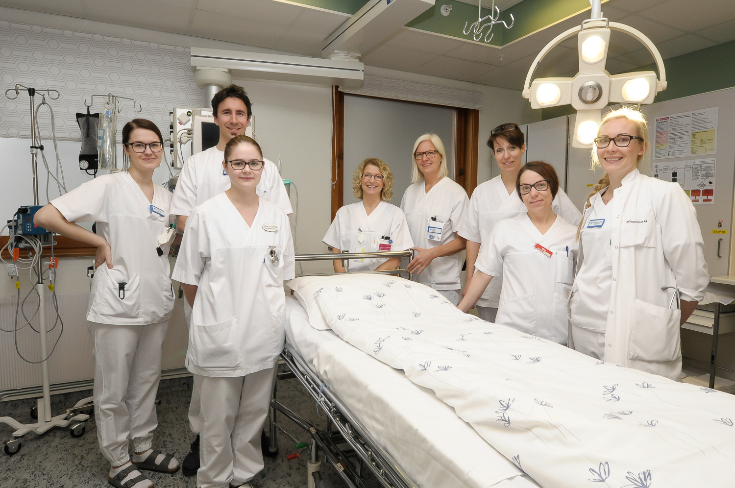 En gruppe mennesker i hvite labfrakker står ved siden av et bord