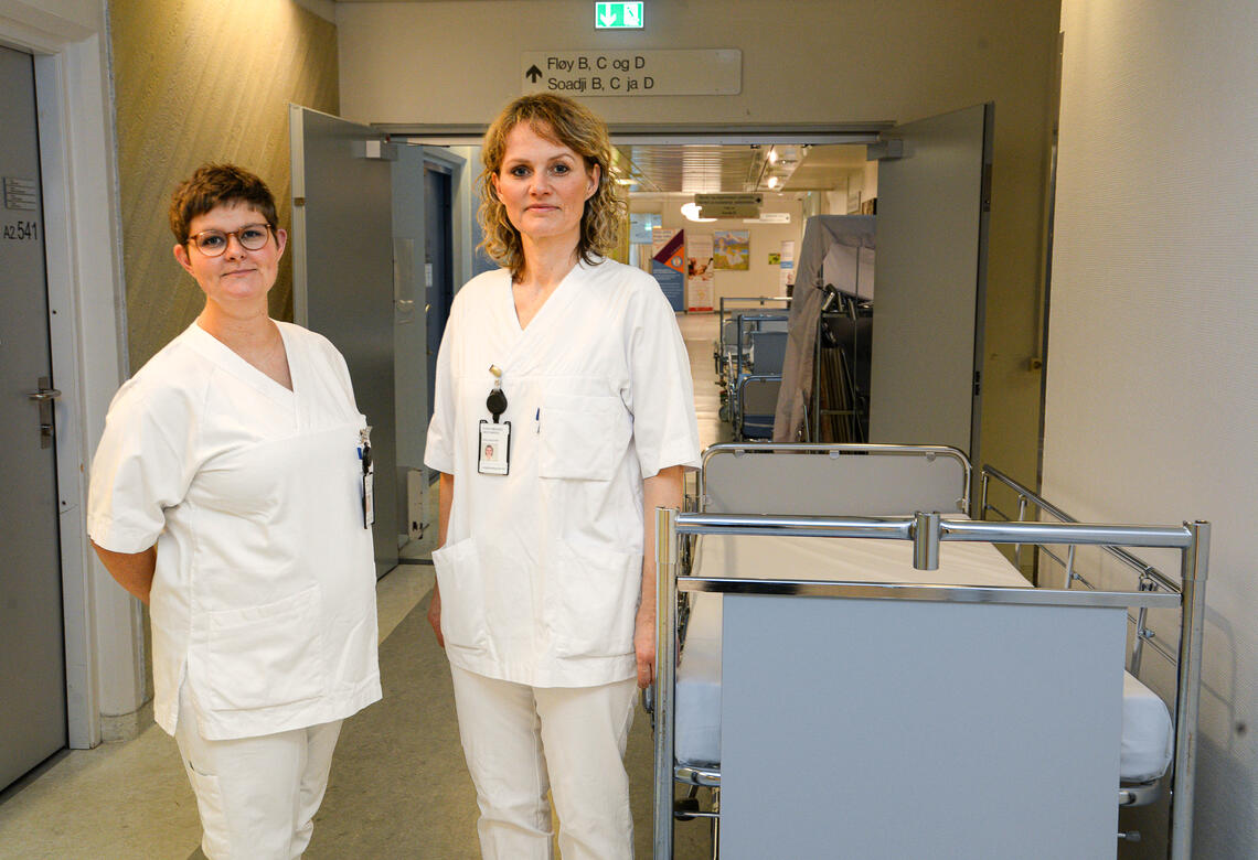 2 sykepleiere stående ved en tom seng i en korridor