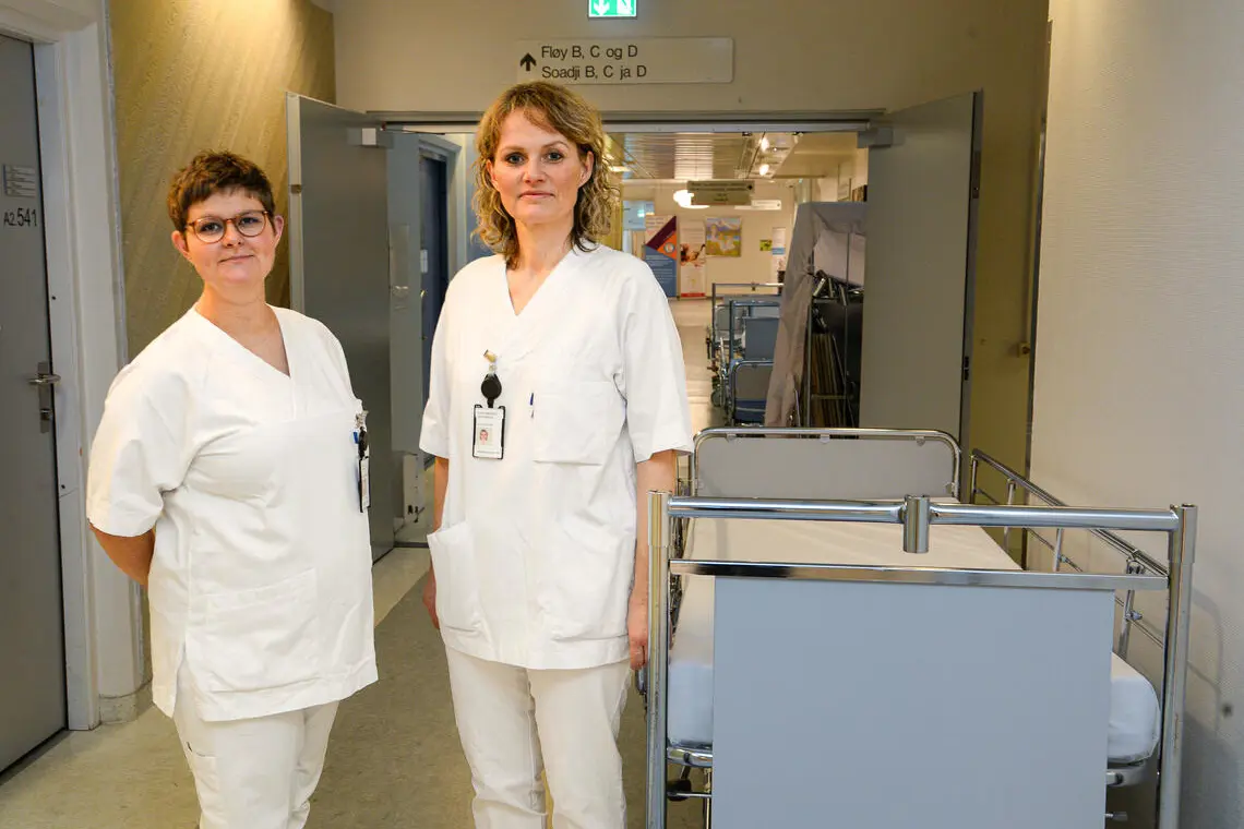 2 sykepleiere stående ved en tom seng i en korridor