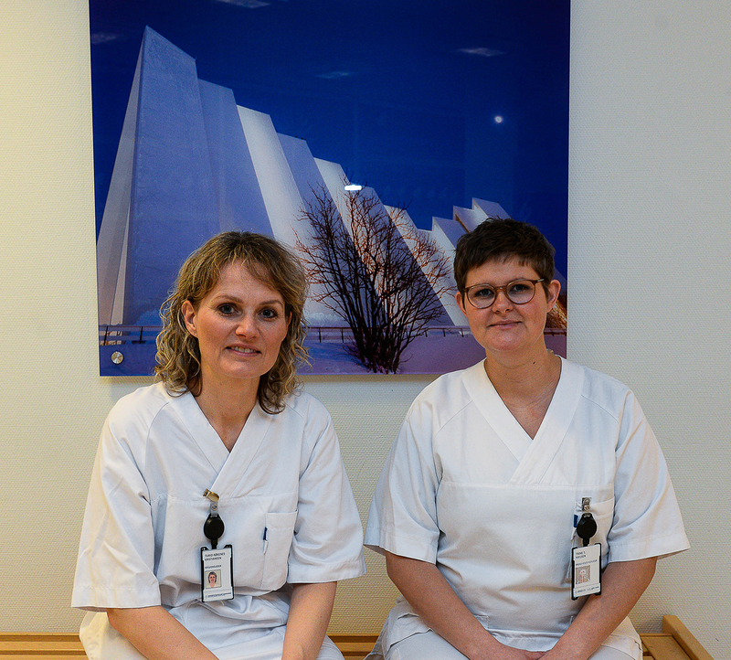 2 sykepleiere sittende foran et bilde av Ishavskatedralen