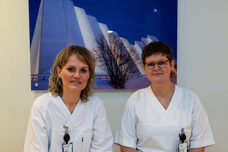 2 sykepleiere sittende foran et bilde av Ishavskatedralen