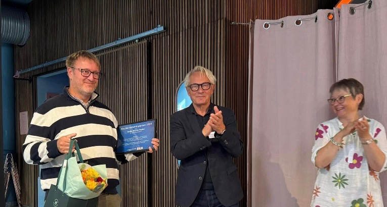 En gruppe mennesker som står foran en blå vegg