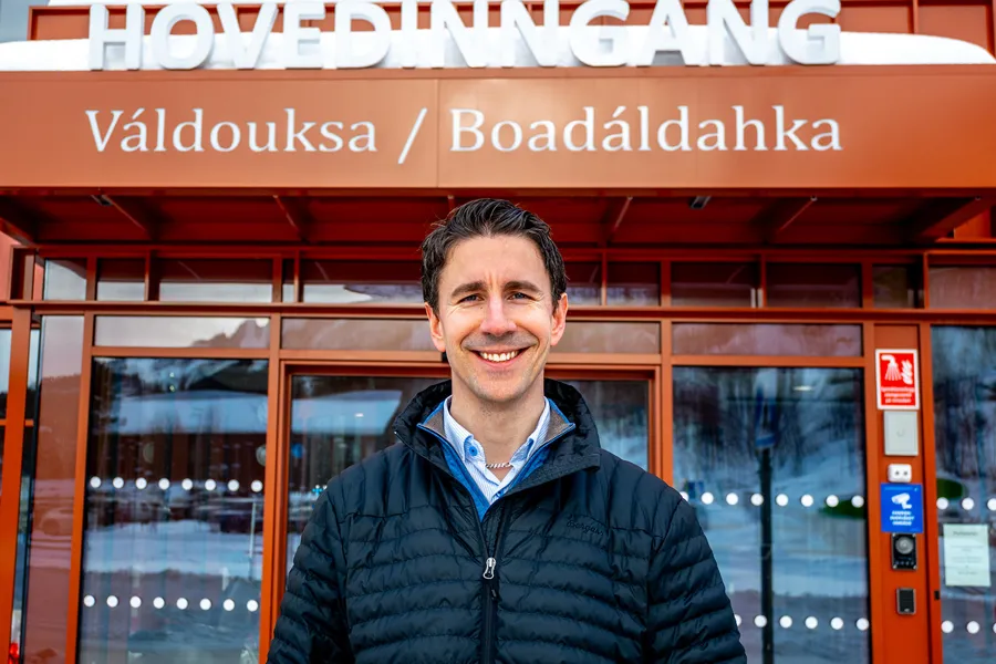 En mann som smiler foran en butikkfasade