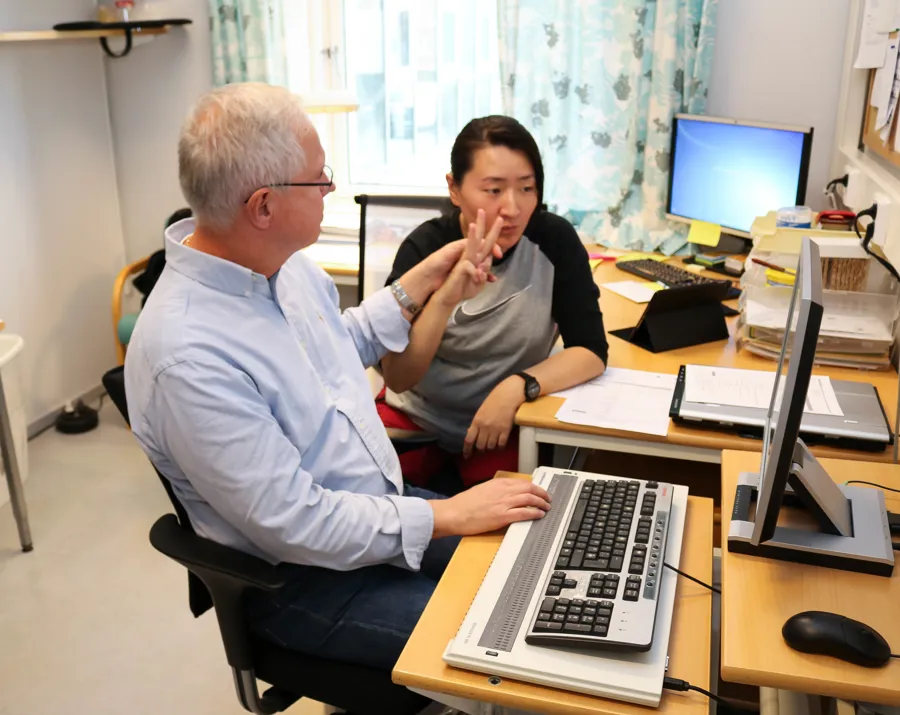 En mann og en kvinne som sitter ved et skrivebord med datamaskiner