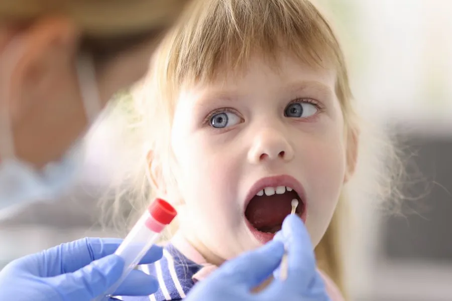 Lege tar prøve fra munnen til en liten jente