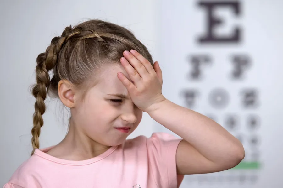 Jente som holder seg for pannen