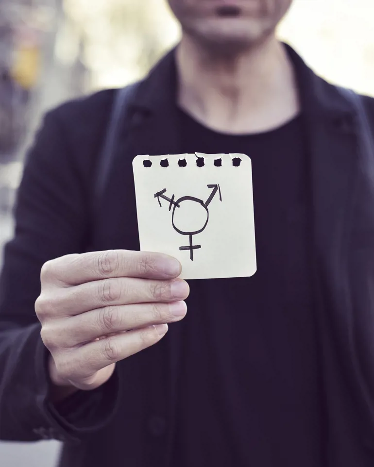 Person som holder i et kort som viser symboler for kjønnsinkongruens