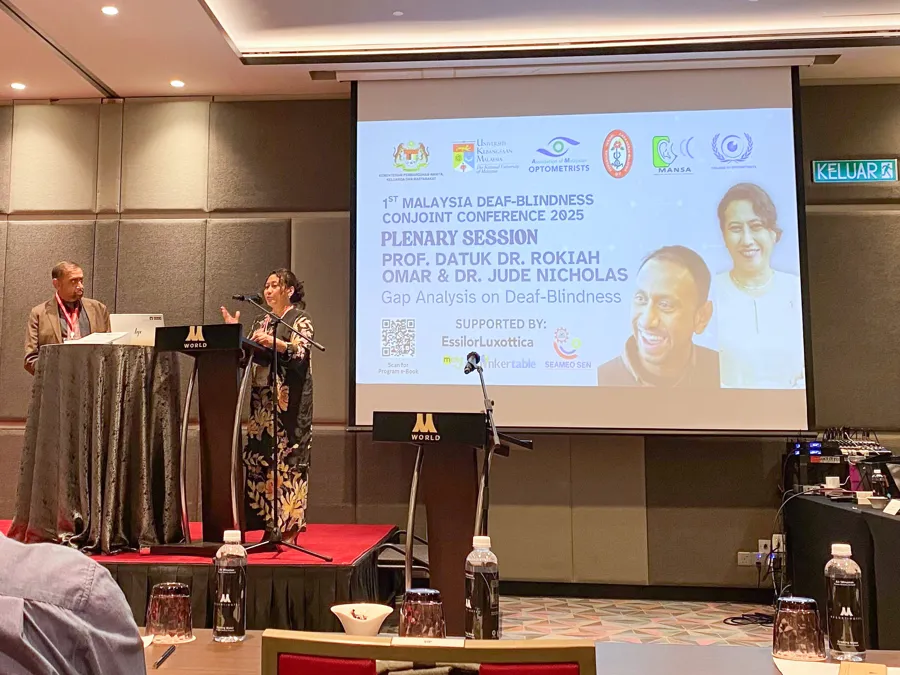 En person som står ved et podium foran en skjerm