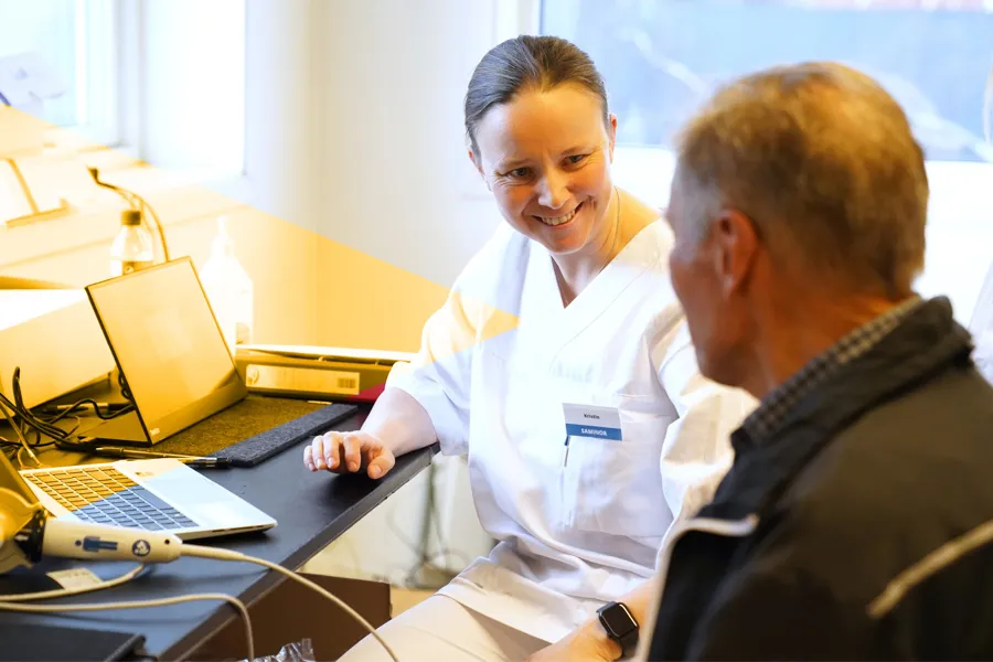 En kvinne som viser en mann noe på datamaskinen