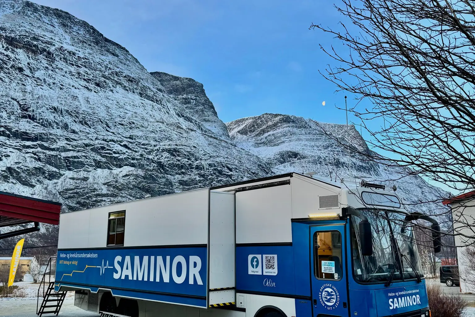 En blå lastebil parkert foran et fjell