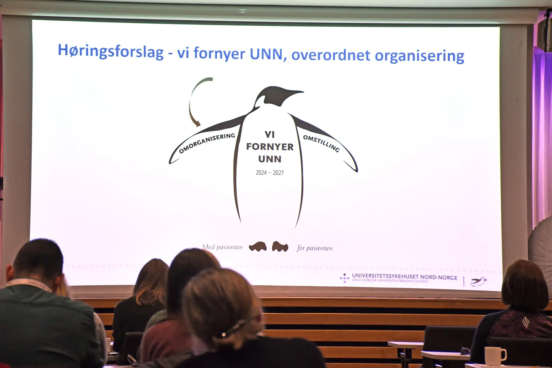 En gruppe mennesker som sitter foran en projeksjonsskjerm